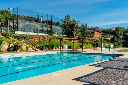 a swimming pool with blue water in a park at Camping El Pasqualet in Caldes de Montbui