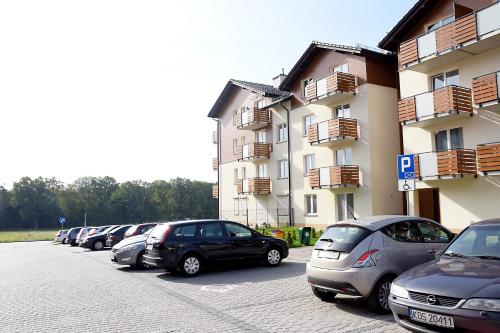 una fila de autos estacionados en un estacionamiento al lado de un edificio en Apartament Umbria 1, en Tychy