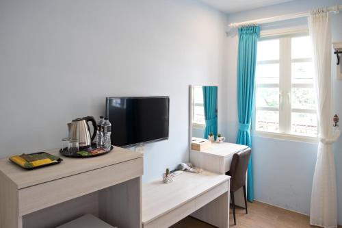 een kamer met een tv aan de muur met een bureau bij Sinyuange B&B in Xinyuan