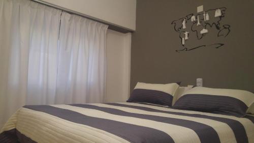 a bedroom with a bed with striped sheets and a window at Dodo Suites in Mar del Plata