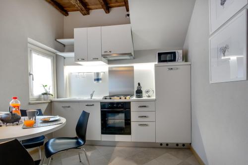 ベルガモにあるLa Cortevecchia 2.0のキッチン(白いキャビネット、テーブル、椅子付)