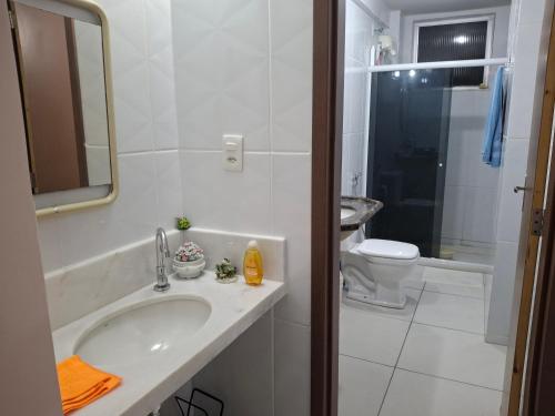 a bathroom with a sink and a toilet and a mirror at Hospedagem Porto Barra in Salvador