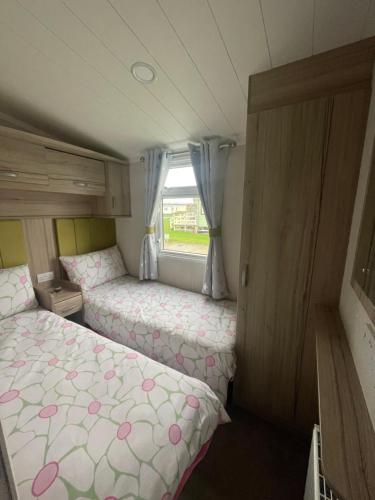 a small room with two beds and a window at Shells at Sandylands in Stevenston