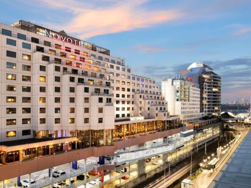 a large white building with traffic in a city at Novotel Sydney Darling Harbour in Sydney