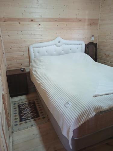 a white bed in a room with a wooden wall at Riverside Cottage in Martvili
