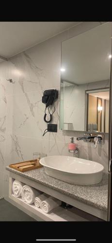 a bathroom with a sink and a mirror and towels at Pristine Pavilion Hotel in Shillong