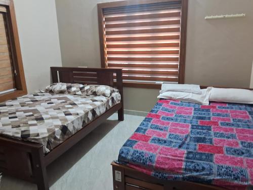a bedroom with two beds and a window at Sree durga Villa Homestay in Kodoth