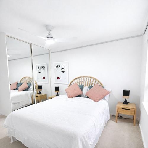 a white bedroom with a white bed and a mirror at Moonya Courtyard in Carnegie