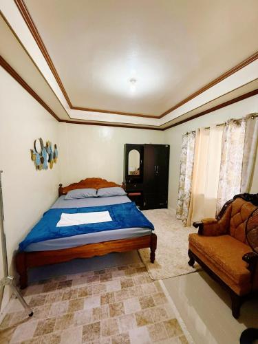 a bedroom with a bed and a couch and a chair at Romar's Place Roxas Orientl, Mindoro in Roxas