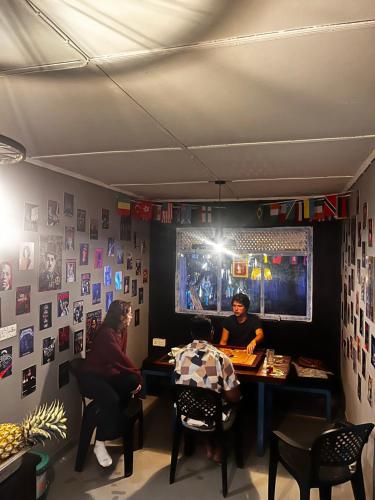 two people sitting at a table in a room at Ella Ceylon Homies Hostel in Ella
