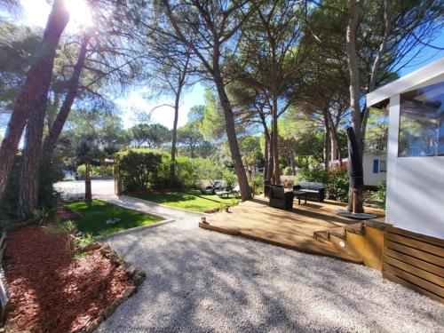 a patio with a bench and trees in a yard at Mobil-home Oasis Village Club in Puget-sur-Argens