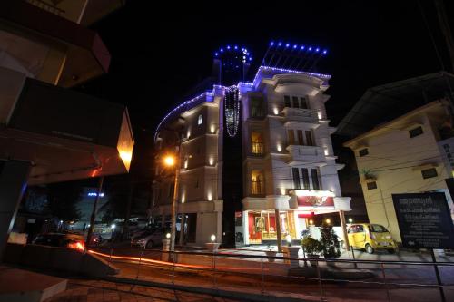 un edificio blanco con luces azules por la noche en Srivar Hotels, en Guruvāyūr