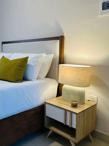 a bedroom with a bed and a nightstand with a lamp at The Kgale Luxe in Gaborone