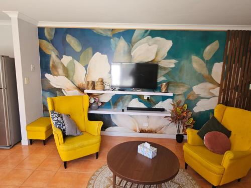 a living room with yellow chairs and a tv at House in Ellenbrook in The Vines