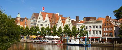 a city with buildings and a river with boats at Hotel Jensen in Lübeck