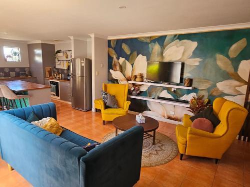 a living room with blue couches and yellow chairs at House in Ellenbrook in The Vines