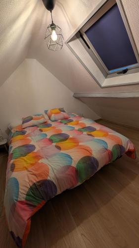 un letto con un piumone colorato in una camera da letto di Chez LouChris a La Baule