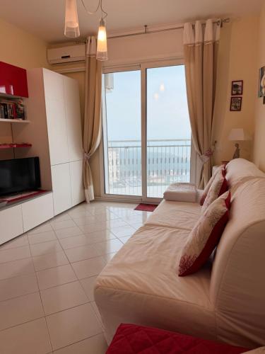 a living room with a couch and a large window at Torre 13F SeaView Studio in Lignano Sabbiadoro