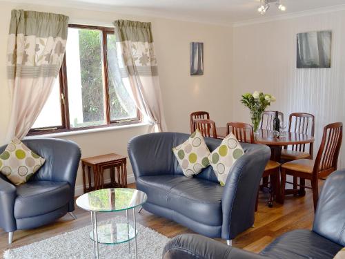 a living room with blue leather chairs and a table at Rosecraddoc Manor - Riverview in Saint Cleer