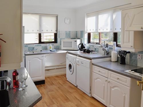 a kitchen with white cabinets and white appliances at Rosecraddoc Manor - Riverview in Saint Cleer