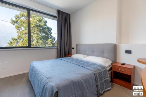 a bedroom with a bed and a large window at SYMPHONY HOUSE by Design Studio in Bellano