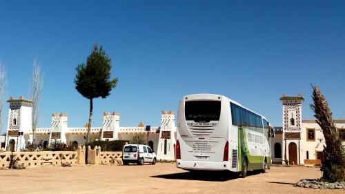 a white bus parked in front of a building at Ksar Timnay Hotel in Aguelmous