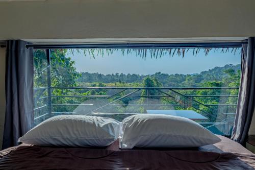 a bed with two pillows in front of a large window at Sunray Hill in Ranong