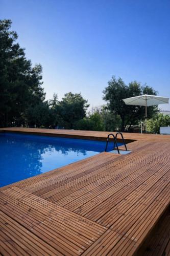 a wooden deck next to a swimming pool with an umbrella at Tenuta Gran Bosco in Loro Piceno