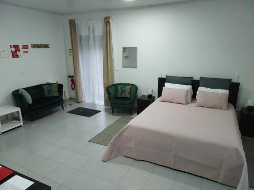 a bedroom with a large bed and two chairs at Retiro das Camélias 3 in Lajes das Flores
