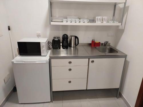 a small kitchen with a microwave and a sink at Retiro das Camélias 3 in Lajes das Flores