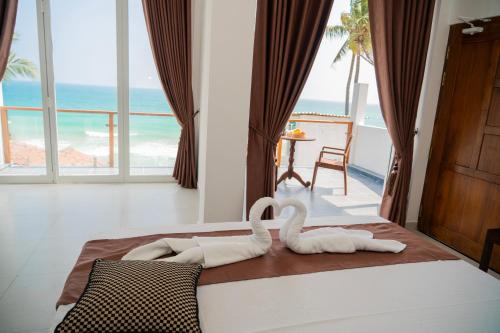two swans sitting on a bed in a room with the ocean at Trinco Beachfront Villas AJS in Trincomalee