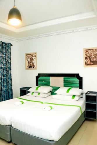 a bedroom with a large white bed with green accents at Silk Mbare Guest House in Manzini