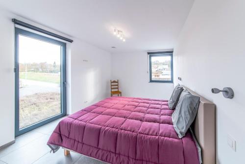 ein Schlafzimmer mit einem lila Bett und einem großen Fenster in der Unterkunft Le Milan in Nassogne