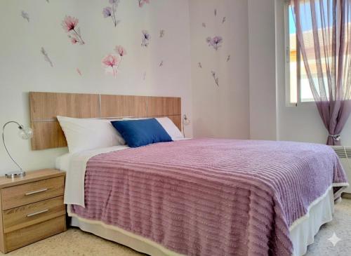 a bedroom with a bed with a purple blanket and a window at Studio Nova in Priego de Córdoba