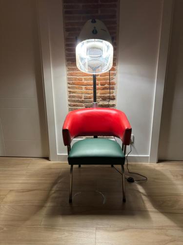 a red chair sitting in a room with a light at Plus in Logroño