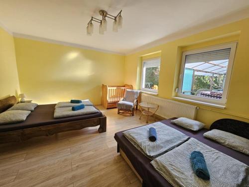 a bedroom with two beds and a chair and a window at Bányász Vendégház in Csokvaomány