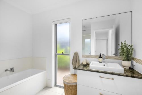 a white bathroom with a sink and a mirror at Mooloolaba Parkway Palms Spacious 3BR with Patio & BBQ Pet-Friendly near the Beach in Mooloolaba