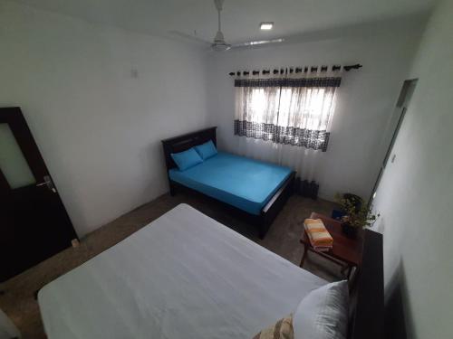 a bedroom with a blue bed and a window at AIRA in Galle