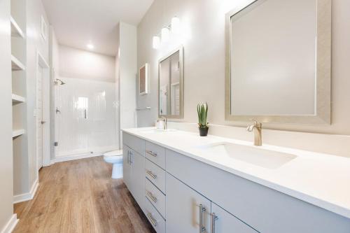 a white bathroom with two sinks and a mirror at Landing Apartments - Sereno in Wimauma
