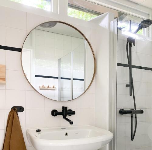 a bathroom with a sink and a mirror at Dromen op 1 - Stijlvol boshuis op de Veluwe met veranda en grote omheinde tuin! in Nunspeet