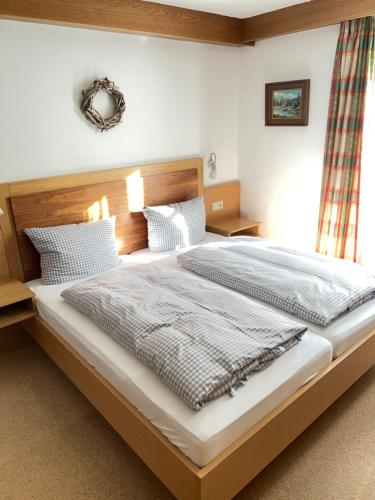 a bedroom with a large bed with a wooden headboard at Das Alpenglühn Hotel & Restaurant in Krün