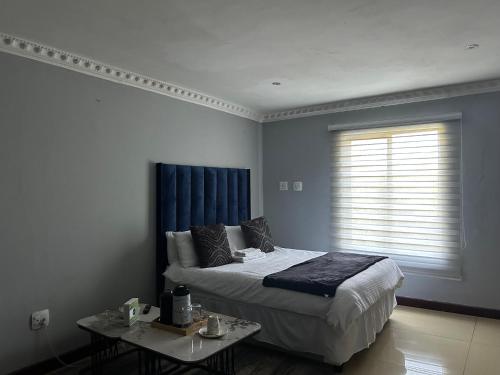a bedroom with a bed and a table and a window at Homely Palace in Midrand