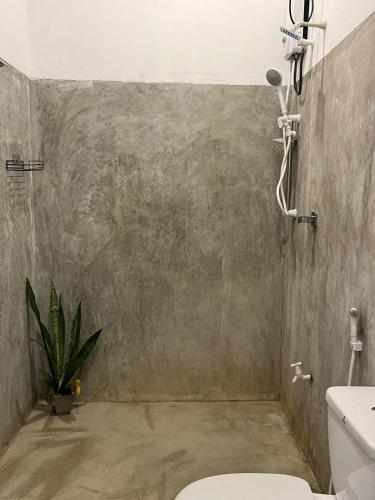 a bathroom with a toilet and a concrete wall at HideWay Guest House Midigama in Midigama East