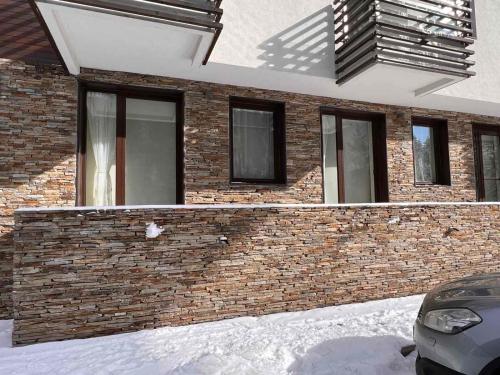 a brick house with a car parked in front of it at Lyra Forest Apartment in Borovets