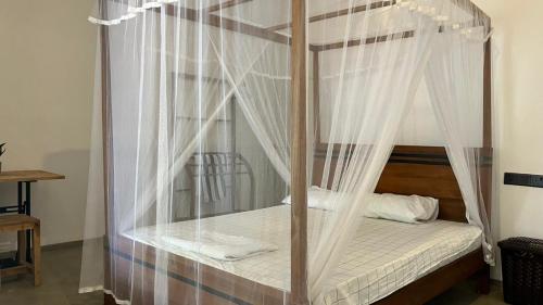 a bedroom with a canopy bed with white drapes at HideWay Guest House Midigama in Midigama East