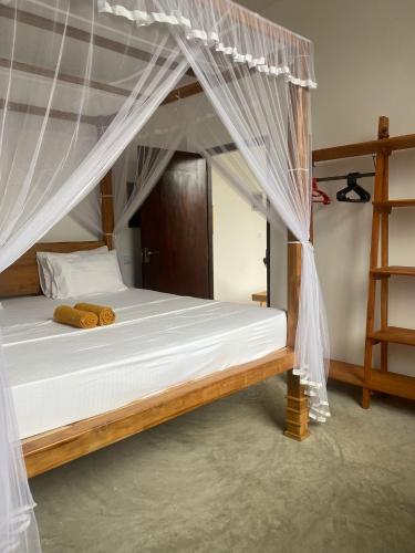 a bed with a canopy in a room at Bamboo Garden Inn in Goiyapana