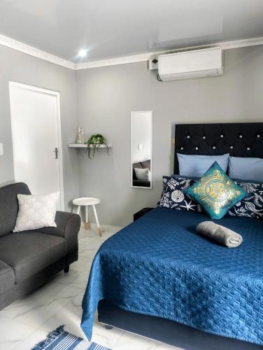 a bedroom with a blue bed and a couch at Roxy's in Richards Bay