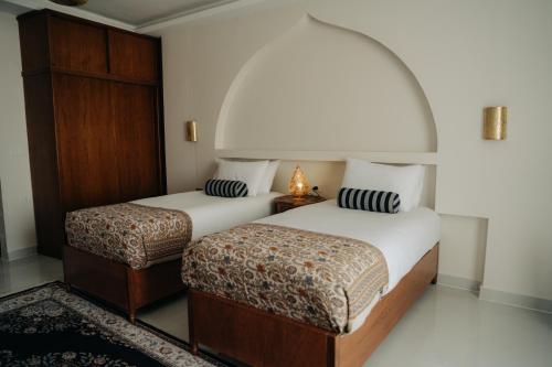 two beds in a room with an arch overhead at Theban Hills Hotel, Luxor in ‘Ezbet Abu Ḥabashi