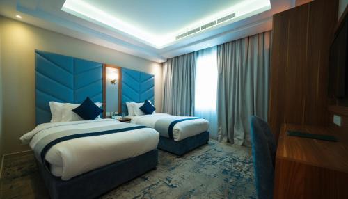 a hotel room with two beds and a window at La Richy Jeddah in Jeddah