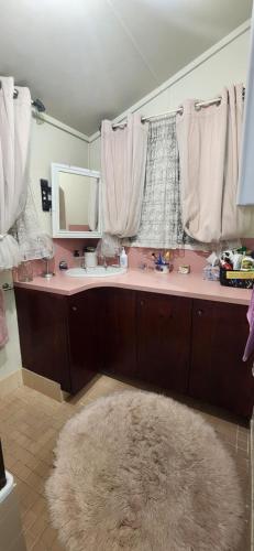 a bathroom with a sink and a mirror and a rug at Meyenburg House in Mount Morgan